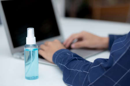Hand of man work from home with alcohol gel or sanitizer for cleaning and protect, new normal, quarantine and social distancing, business and freelance using laptop computer.の写真素材