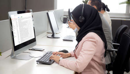 Young businesswoman is muslim or islam and team wearing  headphone with diversity ethnicity while...