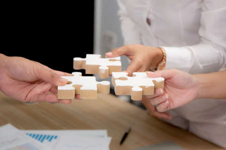 Hands of team young business and partner holding piece jigsaw for assembly is metaphor, teamwork symbol, bonding and harmony in team, friendship and marketing, business and communication concepts.の写真素材