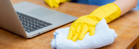 Hand of young asian woman cleaning and wipe laptop computer with disinfect and alcohol for protect...