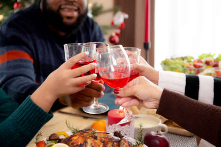 Happy family in party with fun on Christmas holiday together at home, festive celebration thanksgiving eve or xmas, diversity of ethnicity, new year with parent and children eating and drinking.の写真素材