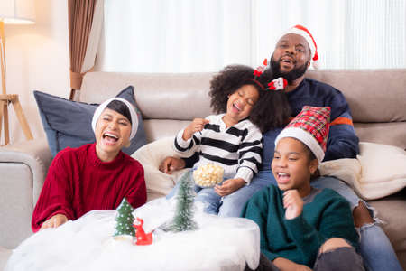 Happiness African family mom and dad and daughter watching tv and laughing with fun and enjoyment in the living room at home, family leisure with television for comfortable in Christmas day.の写真素材