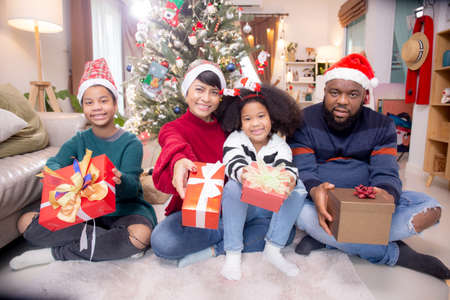 Happy family father and mother and daughter sitting and having gift box at home, celebration in xmas...