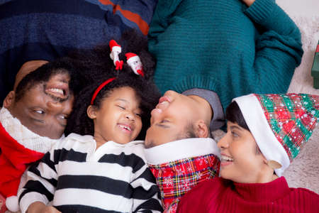 Happy African family lying smiling on Christmas day together while gift box on floor, top view,...