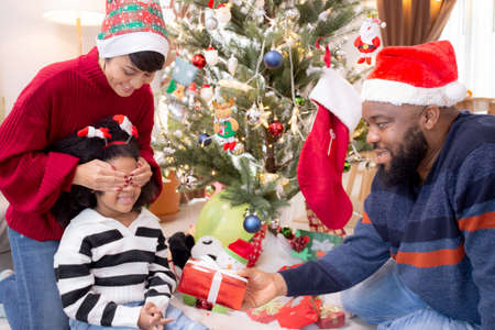 Happy family father and mother close eye daughter and giving gift box on celebration in Christmas day at home, xmas with parent surprising children at house, thanksgiving eve, Merry Christmas.の写真素材