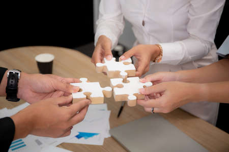 Hands of team young business and partner holding piece jigsaw for assembly is metaphor, teamwork...