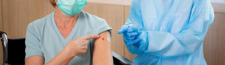 Doctor woman holding syringe and injection vaccine patient elderly in face mask at hospital, vaccination for pandemic of senior, infection and immunization, medical concept.の写真素材