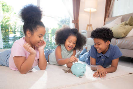 Happiness African family with children saving money in piggy bank for planning future of expense for financial success, deposit and investment, domestic life, business and finance concept.の写真素材