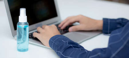 Hand of man work from home with alcohol gel or sanitizer for cleaning and protect coronavirus or covid-19, new normal, quarantine and social distancing, business and freelance using laptop computer.の写真素材