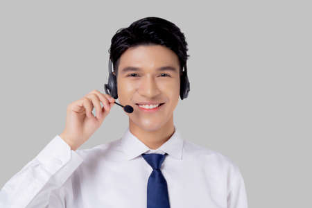 Portrait young asian business man call center wearing headset isolated on white background, agent with support and service, businessman is assistant for client with phone or helpline online.の写真素材