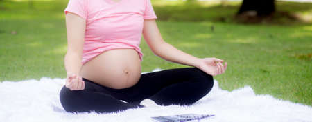 Happiness young asian woman pregnant sitting doing yoga with meditation lotus for relaxation in the...