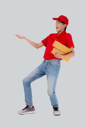 Young asian man in uniform red and cap standing carrying box stack isolated white background, employee holding cargo or package, courier and delivery, transportation and service, logistic concept.の写真素材