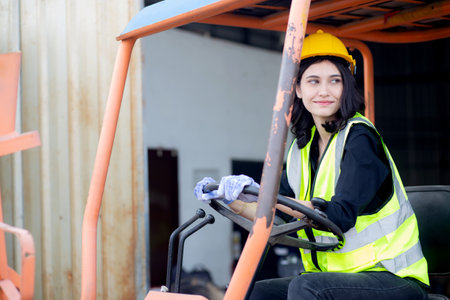 Young asian woman is foreman driving forklift at distribution warehouse, engineer working and shipping container at factory, cargo and logistic, one person, industry and transport concept.の写真素材