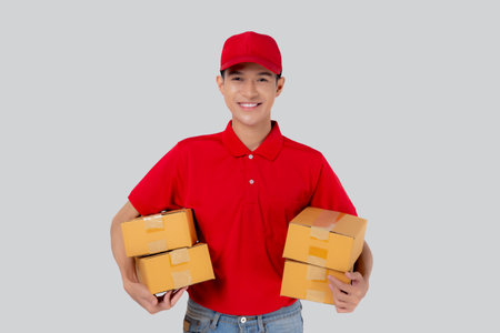 Young asian man in uniform red and cap standing carrying box stack isolated white background,...