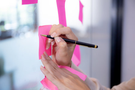 Hands of businesspeople and colleagues brainstorm for planning and strategy of businesswoman and marketing at office, team meeting for creative with writing on post it sticker, business concept.の写真素材
