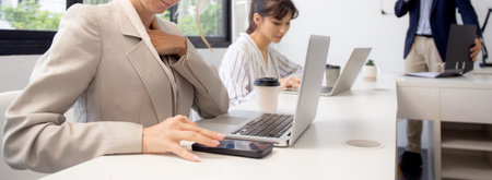 Young caucasian businesswoman using laptop computer and smart phone working at the office, woman and colleagues working with confident at workplace, startup business concept.の写真素材