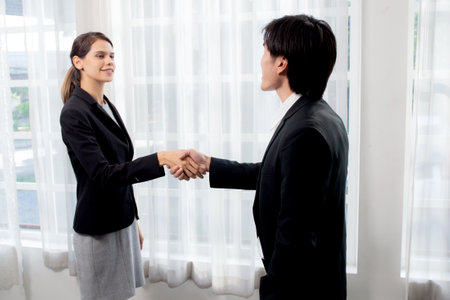 Happy business man and woman standing and shake hands while agreement of negotiation success and congratulations at office, businessman and partner handshake while greeting together, business concept.の写真素材