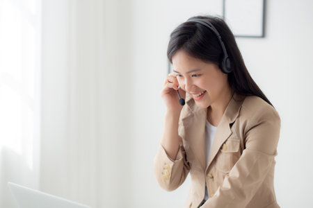 Young asian businesswoman wearing headset video call and explain conference online at home, woman wearing headphone meeting and talking for working from home, business and communication concept.の写真素材