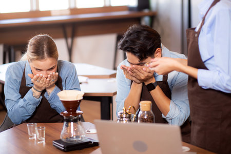 Young man and woman learning making coffee and sniff bean with barista while laptop on desk at cafe, group people training drip coffee with entrepreneur, small business or SME.の写真素材