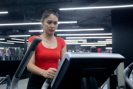 Portrait young asian woman walking on treadmill in fitness gym, cardio exercise, sport and training, health and wellness, female doing challenge with workout and exercise, motivation and dedication.の写真素材