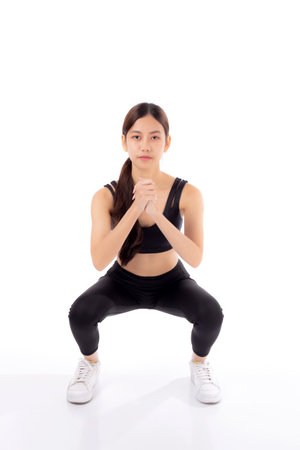Full length portrait beautiful young asian woman in sportswear practicing doing squats for bodybuilder isolated white background, woman workout for strong and strength, sport and endurance concept.の写真素材