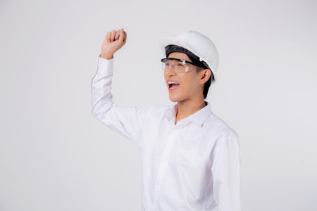Portrait young asian engineer man wearing helmet excited isolated white background, male is architect or contractor with glad and success, contractor proud and satisfied, industrial concept.の写真素材