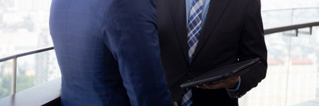 Senior businessman standing talking with partner and looking digital tablet together at office, manager discussing and meeting about project with consultant professional, business concept.の写真素材