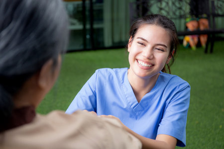 Caregiver asian woman care elderly sitting on wheelchair, consoling for encourage in garden at hospital, senior therapy and rehabilitation with doctor for rehab and treatment, insurance and medical.の写真素材
