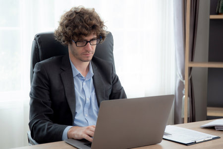 Young caucasian businessman using laptop computer planning for success in modern office, businessman typing on notebook with confident, executive or manager with handsome, business concept.の写真素材