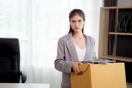 Portrait young woman employee carrying cardboard box or belonging with frustrated and stress while fired from job with despair, businesswoman resign with hopeless and sad, business and unemployment.の写真素材