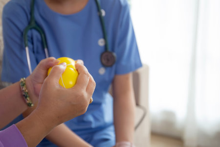 Closeup hands senior woman holding ball for massage while caregiver or nurse training physical therapy and rehabilitation, caretaker or physiotherapist helping elderly physiotherapy, medical concept.の写真素材