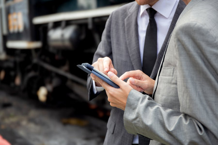 Closeup hands young engineer man and woman in suit checking train with tablet in station, team engineer inspect system transport, technician examining infrastructure, transportation and industry.の写真素材