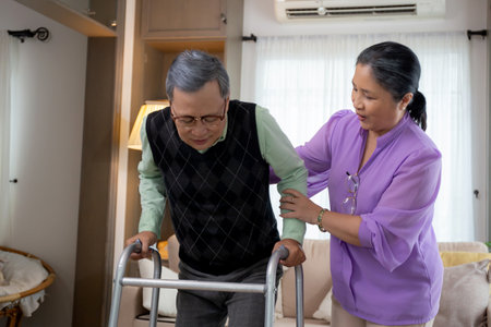 Asian senior woman helping and support elderly man while walking with walker for rehabilitation and...