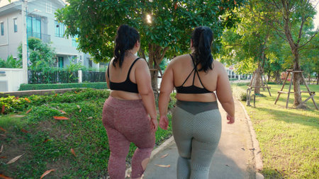 Two asian woman fat in sportswear jogging together on pathway at park, woman and friends obesity doing activity with cardio or walking, workout and exercise, plus size and health for weightloss.の写真素材