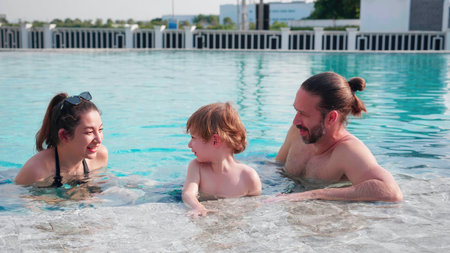 Caucasian family having enjoy and fun together with happiness in swimming pool, summer and holiday, mom, dad and son relax and playful, summertime and vacation, relation and bonding, family concept.の写真素材
