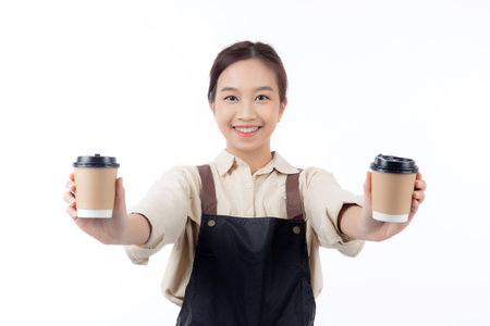 Cheerful young asian woman barista in casual work attire happily holding a takeaway coffee cup, isolated white background, joyful barista presenting takeaway coffee, small business or startup.の写真素材