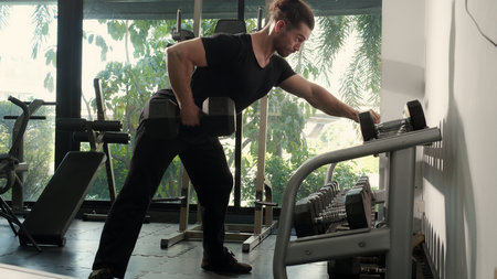 Young caucasian man training exercise or workout with lifting dumbbell for bodybuilder with strong...