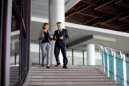 Two senior business man and woman in formal meeting and discussing documents and using a tablet in...