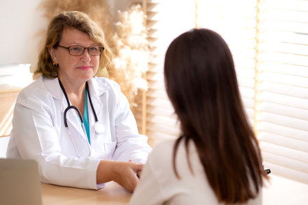 Senior woman doctor examining elderly while holding arm for pulse sitting in modern medical office, doctor checkup patient, patient and insurance, medical and health, doctor discussing with patient.の写真素材