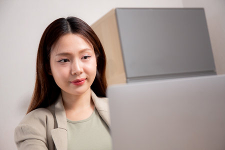 Young asian woman sitting and using laptop computer planning for success in modern office, businesswoman typing and watching notebook with confident, employee working on desk, business concept.の写真素材