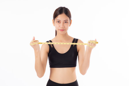 Portrait happy young asian woman in sportswear holding measure tape isolated white background, girl care body with workout or exercise, dieting and cellulite, sport and loss weight for health.の写真素材