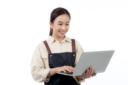 Portrait young asian business woman wearing apron holding laptop computer isolated white background, waitress or barista holding laptop computer with confident, cut out, business or freelance.の写真素材