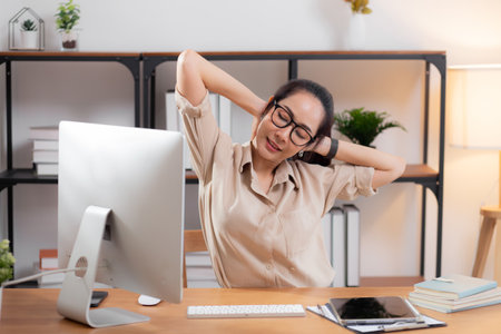 Portrait young asian businesswoman wearing glasses taking a break after overworked with stretching arm and hand in living room at home office, business woman relax with ergonomic, business and health.の写真素材