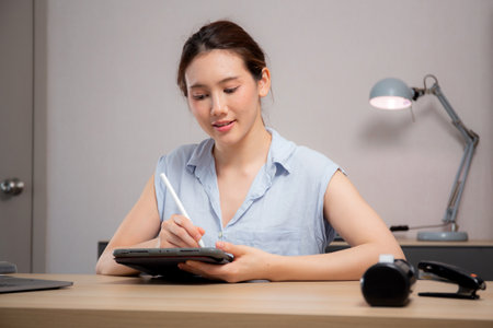 Young caucasian business woman using digital tablet with stylus in modern home office, businesswoman working at home with tablet in living room, education and learning, business and marketing.の写真素材