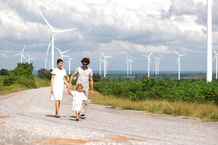 Happiness family walking wind turbine farm while father and daughter mother walking together,...