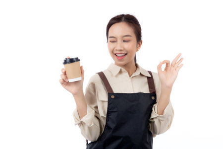 Portrait young asian woman barista holding a takeaway coffee cup with excited gesture ok isolated white background, happy barista presenting takeaway coffee with success, small business or startup.の写真素材