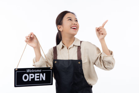 Portrait young asian barista woman wearing apron holding open sign for inviting customer to enter with happiness, waitress woman holding signboard with open, small business or startup business.の写真素材