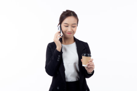 Portrait cheerful young asian businesswoman holding coffee cup while talking smart phone with relax and satisfied isolated white background, business woman drinking coffee and speaking on smartphone.の写真素材