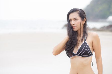 Beautiful young asian woman standing with happiness for relax on beach in tropical, happy woman in bikini with expression relaxation in holiday, recreation and leisure in summer.の写真素材
