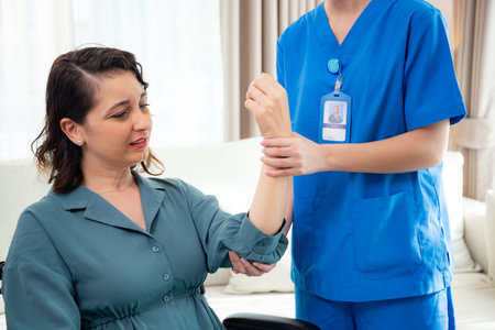 Young nurse therapy with patient while stretching muscle hand in living room at home, doctor woman support and rehabilitation with patient, caregiver and service with woman, medical and rheumatism.の写真素材